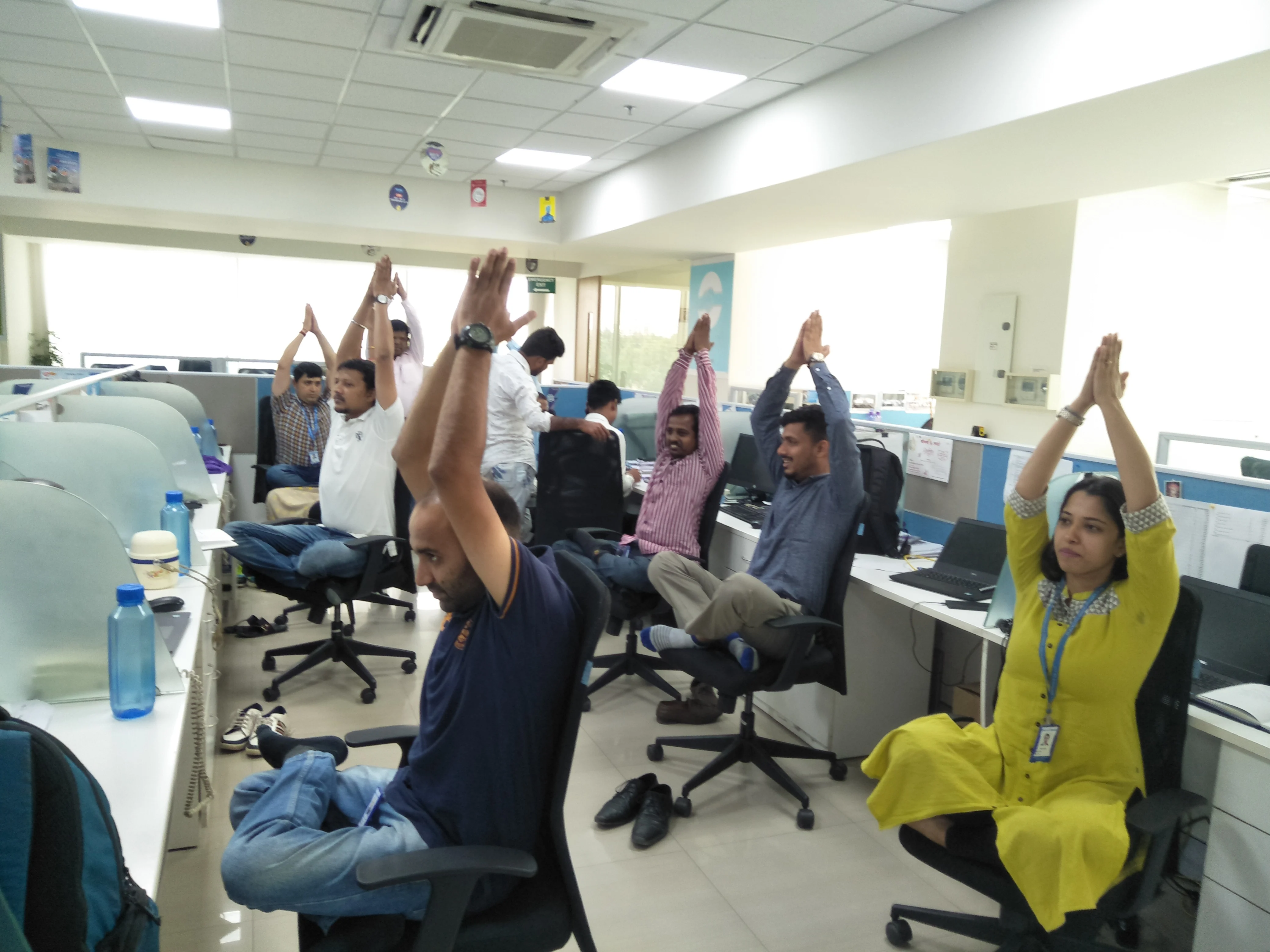 Employees doing desk yoga stretches at their workstations